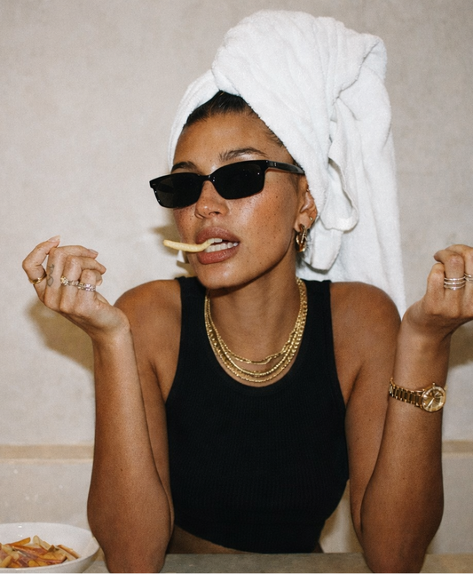Woman eating pasta with a towel on her head in a casual setting